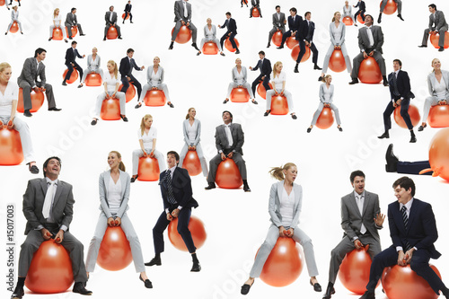 Foto: Large group of business people bouncing on inflatable balls, studio shot Large group of business people bouncing on inflatable balls, studio shot