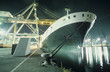 Containership being loaded in dock at night