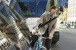 Man standing by bicycle on busy street