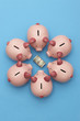 Piggy banks surrounding roll of dollar bills, blue background, view from above