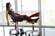 Professional woman resting her legs up on office chair