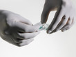 Photo: Person wearing rubber gloves putting powder into vial, close up, studio shot Person wearing rubber gloves putting powder into vial, close up, studio shot
