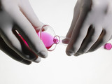 Photo: Person wearing rubber gloves pouring pink liquid into vial, close up, studio shot Person wearing rubber gloves pouring pink liquid into vial, close up, studio shot