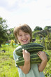 Boy holding marrow in garden, portrait