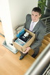 Businessman on office staircase with box of belongings