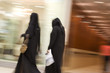 dubai uae two women dressed in traditional abayas and hijabs black robes and scarves.