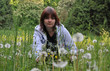 a young woman in the filed with dandelions a young woman in the filed with dandelions