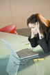 Businesswoman looking at laptop holding her head