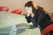 Businesswoman looking at laptop holding her head