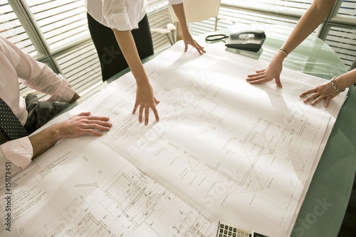 Foto: Closeup of professionals looking at architectural plans on desk Closeup of professionals looking at architectural plans on desk