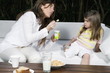Young woman and girl having breakfast outdoors