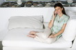 Young woman on couch talking on phone