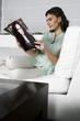 Young woman on couch reading magazine