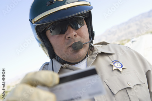 Photo: Highway patrol officer examines driving license Highway patrol officer examines driving license