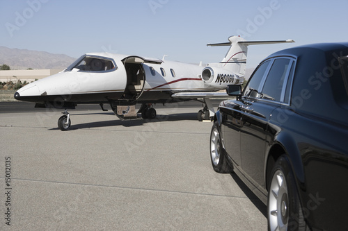 Foto: Limousine and private jet on landing strip. Limousine and private jet on landing strip.
