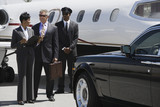 Photo: Mid-adult businesswoman, senior businessman and chauffeur in front of private airplane. Mid-adult businesswoman, senior businessman and chauffeur in front of private airplane.