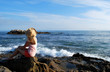 A woman in a big hat overlooks the ocean