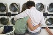 Young couple washing clothes at launderette