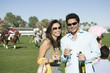 Couple toasting on polo field, portrait