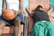Two Young Man Relaxing on Sunlounger, One with Basketball