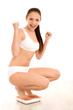 Young woman crouching on a weighing scale