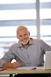 Portrait d'un homme souriant assis à un bureau