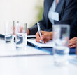 Half filled water glass, business woman making a note