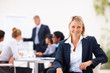 A cute business woman smiling confidently while sitting in the o