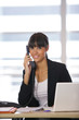 Femme souriante au téléphone devant un ordinateur portable Femme souriante au téléphone devant un ordinateur portable