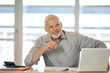 Homme souriant assis à un bureau devant un ordinateur portable Homme souriant assis à un bureau devant un ordinateur portable