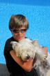 Junge mit Sonnenbrille mit seinem Hund am Swimming Pool
