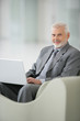 homme d'affaires souriant dans un fauteuil devant un ordinateur