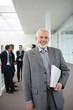 Homme souriant en costume avec un ordinateur portable fermé