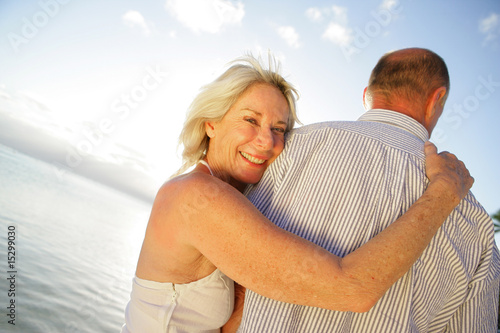 Femme senior souriante près d'un homme au bord de la plage
