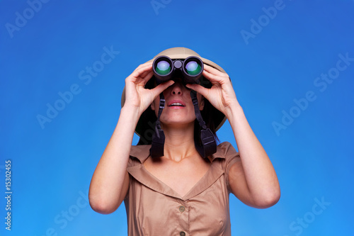 Photo: Woman in safari hat looking through binoculars Woman in safari hat looking through binoculars