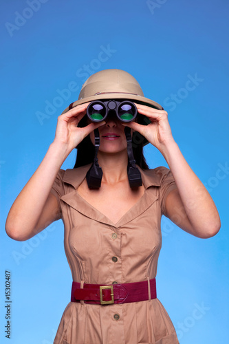 Photo: Woman in safari hat looking through binoculars Woman in safari hat looking through binoculars