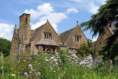 Photo: gable roof with chimney stacks. bay windows. flowers. house gable roof with chimney stacks. bay windows. flowers. house