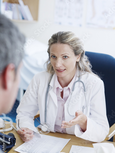 Photo: Female doctor at desk talking to man Female doctor at desk talking to man