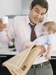 Father holding baby daughter while talking on phone in kitchen