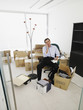 Photo: Male office worker talking on phone while sitting in a new office surrounded by boxes Male office worker talking on phone while sitting in a new office surrounded by boxes