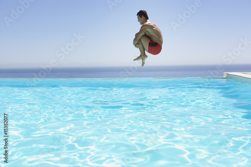 Photo: Man leaping into infinity pool Man leaping into infinity pool