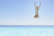 Woman leaping into infinity pool