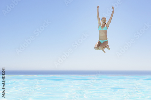 Photo: Woman leaping into infinity pool Woman leaping into infinity pool