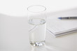 Closeup of glass of water with pen and notebook