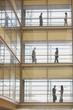 People in silhouette on multiple levels of corridor through glass