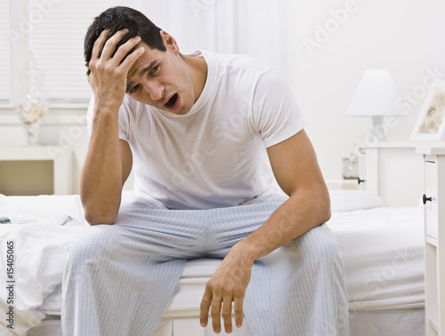 Photo: Attractive Man Sitting on His Bed and Yawning Attractive Man Sitting on His Bed and Yawning