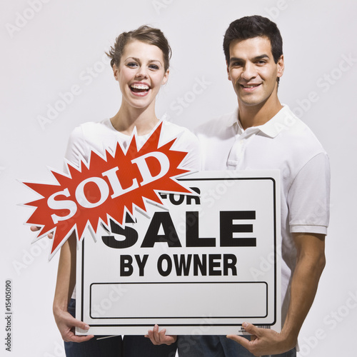 For Sale By Owner Sign. Couple with For Sale by Owner Sign