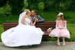 Photo: Kissing newly-married couple on a bench with the little girl Kissing newly-married couple on a bench with the little girl