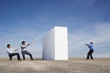 Two men and one man having tug of war with rope over wall