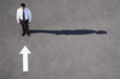Arrow on pavement pointing toward businessman
